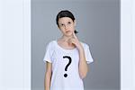 Girl wearing tee-shirt printed with question mark, touching face, looking up