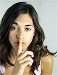 Woman holding finger on lips, looking at camera, portrait