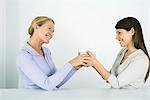 Two women face to face, exchanging gift, smiling at each other