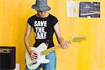 Young man playing guitar, wearing "save the planet" tee-shirt