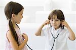 Little boy listening to girl's heart with stethoscope