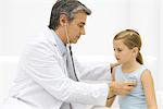 Doctor listening to little girl's heart with stethoscope, side view