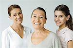 Grandmother, daughter, and preteen granddaughter, smiling at camera, portrait