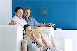 Family together in living room, parents smiling at camera, teen girl listening to headphones