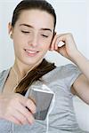 Teen girl listening to MP3 player, smiling, looking down