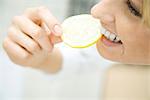 Woman biting into slice of lemon, smiling, close up