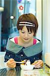 Young Japanese woman eating ice cream sundae