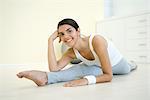 Young woman doing splits, leaning on elbow, smiling at camera