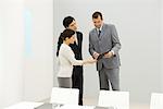 Professionals standing in conference room, looking down at folder