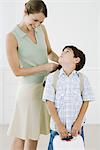 Mother adjusting son's backpack, boy looking up at her