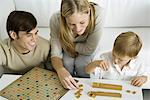 Family playing board game together, mother arranges game pieces