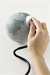 Hand holding stethoscope on small globe