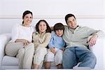 Family sitting together on sofa, looking away