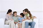 Familie mit drei Kindern zusammen sitzen auf dem Sofa, im Gespräch