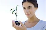 Woman holding seedling in small planter made from discarded light bulb