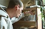 Young man selecting CD from collection on shelf