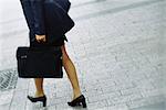 Businesswoman walking on sidewalk, cropped view