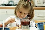 Girl putting jam on bread