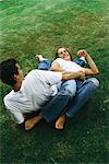 Couple reclining on ground together, laughing, high angle view