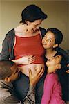 Husband and children gathered around pregnant woman, smiling