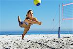 Female playing beach volleyball, diving to catch ball