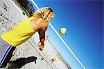 Male volleying beachball over net