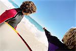 Surfers on beach, one pointing to distance offshore