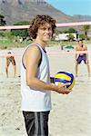 Male holding volleball, playing beach volleyball