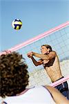 Male playing beach volleball, preparing to hit ball