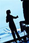 Silhouette of woman traveler standing with luggage cart looking away in airport