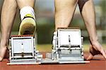 Runner crouching on starting blocks, cropped rear view