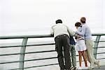 Family together at seawall railing looking at view