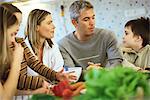Family together in kitchen, raw vegetables on counter