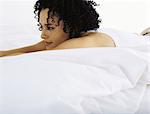 Woman lying on bed, looking away in thought