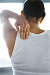 Woman massaging her shoulder, rear view