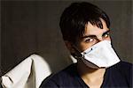 Adolescent portant le masque de la grippe, regardant la caméra