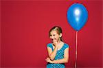 Girl with hand under chin, balloon suspended behind her