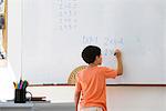 Elementary school student working math equations on whiteboard