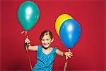 Girl standing with balloons, smiling, portrait