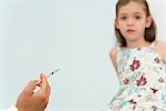 Doctor holding syringe, preparing to vaccinate little girl, cropped