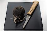 Black radish on cutting board with knife, ready to be peeled