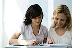 High school teacher and student reading notebook together