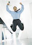Businessman jumping with joy in lobby of office building