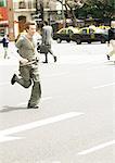 Young man running across city street