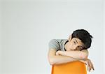 Young man sitting, leaning head on back of chair