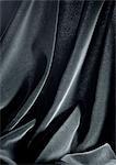 Folds in shiny black fabric, close-up, full frame