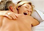 Man embracing laughing woman in bed.