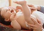 Adult playing with baby lying on table.