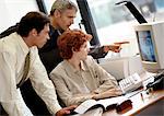 Two businessmen and a businesswoman looking at computer screen