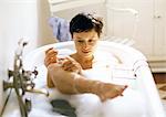 Woman taking bath, holding leg out of water